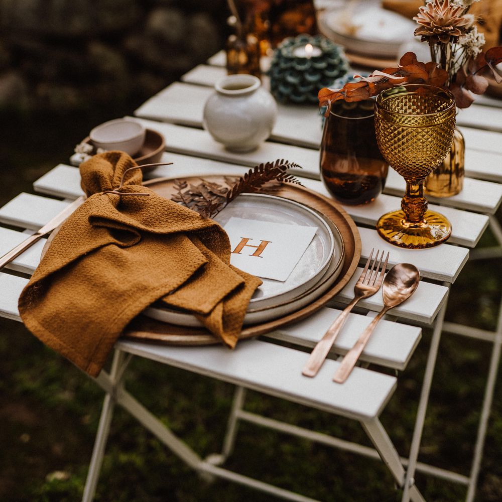 Rustic table decor with orange napkins and small floral bouquets