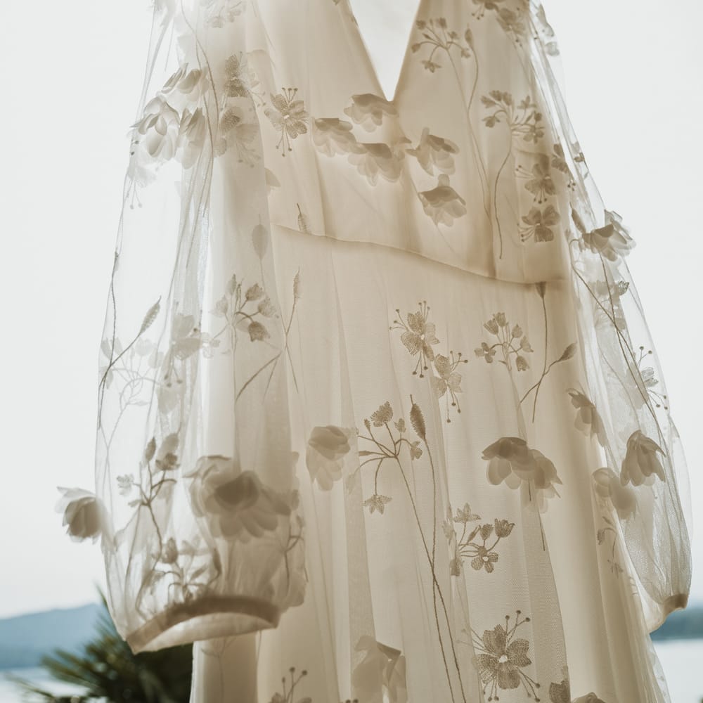 white wedding dress with flowers detail hanging up 