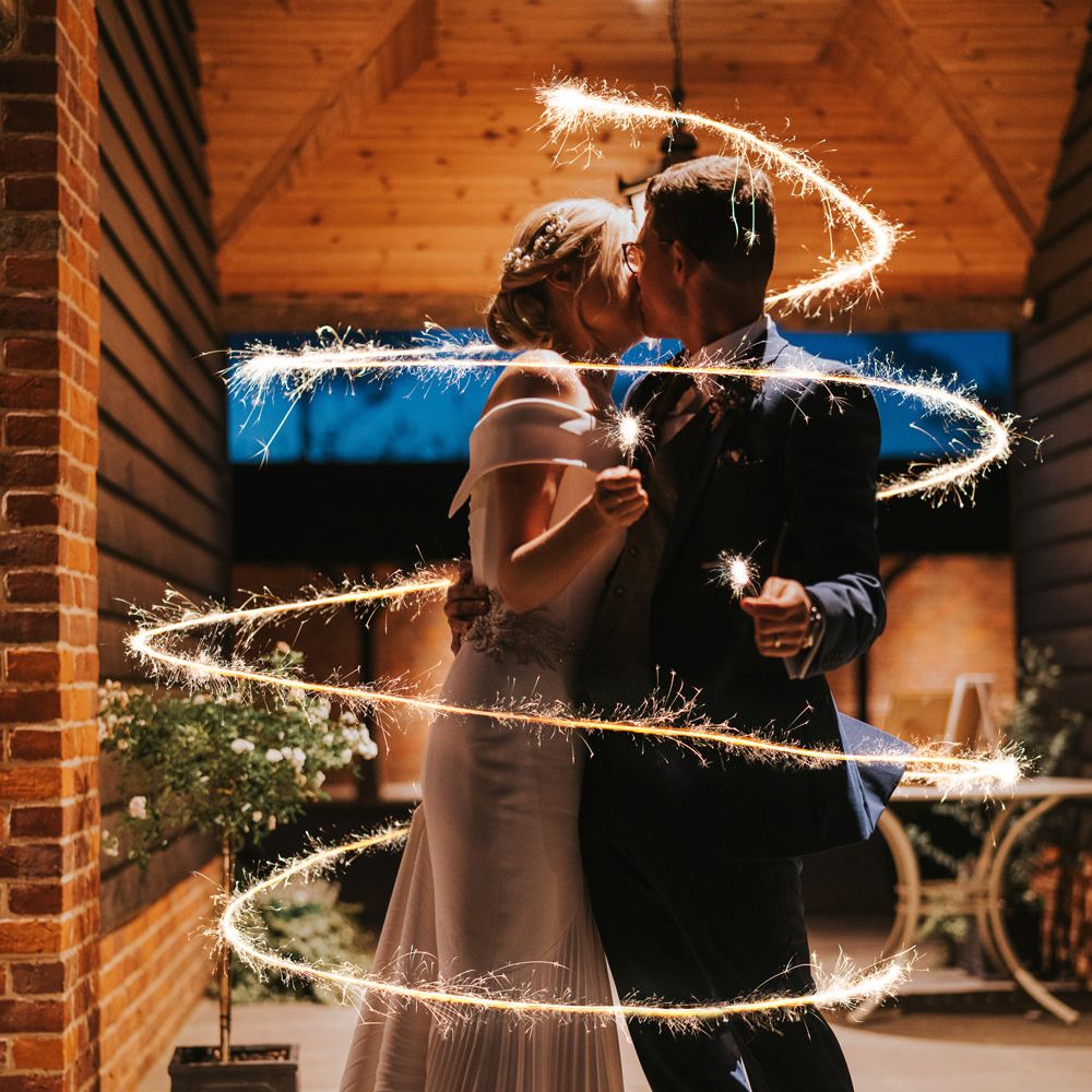 Bride & groom hold sparklers and a ring of light surrounds them from top to bottom