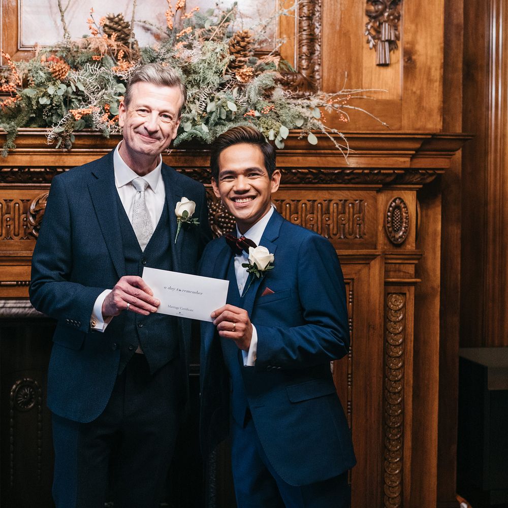 Grooms in front of wooden fireplace 