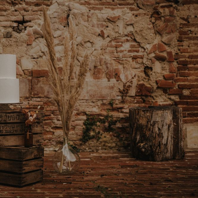 Cake display on wooden crates with apothecary jar filled with pampas grass 