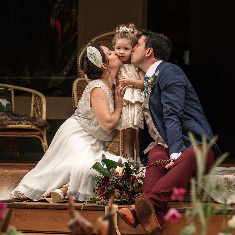 Bride & groom kiss outdoors whilst sat down