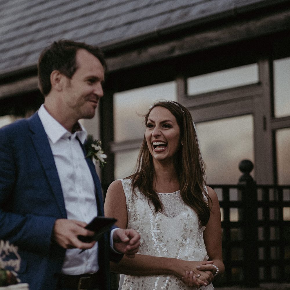 Bride & groom laugh together outdoors on their wedding day