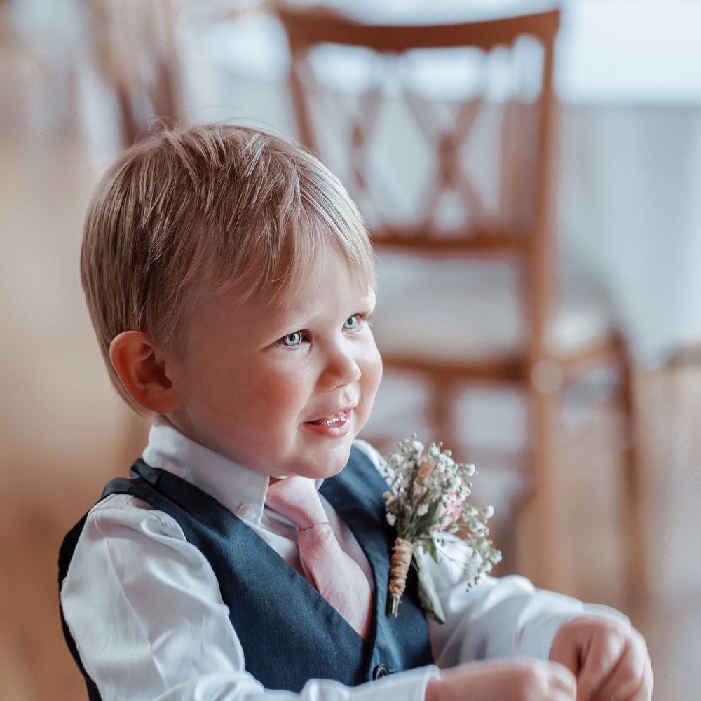 Little boy wears blue waistcoat and pink tie