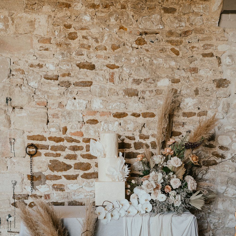 Wedding cake table with buttercream wedding cake and dried and fresh flower arrangements including roses, pampas grass and orchids 