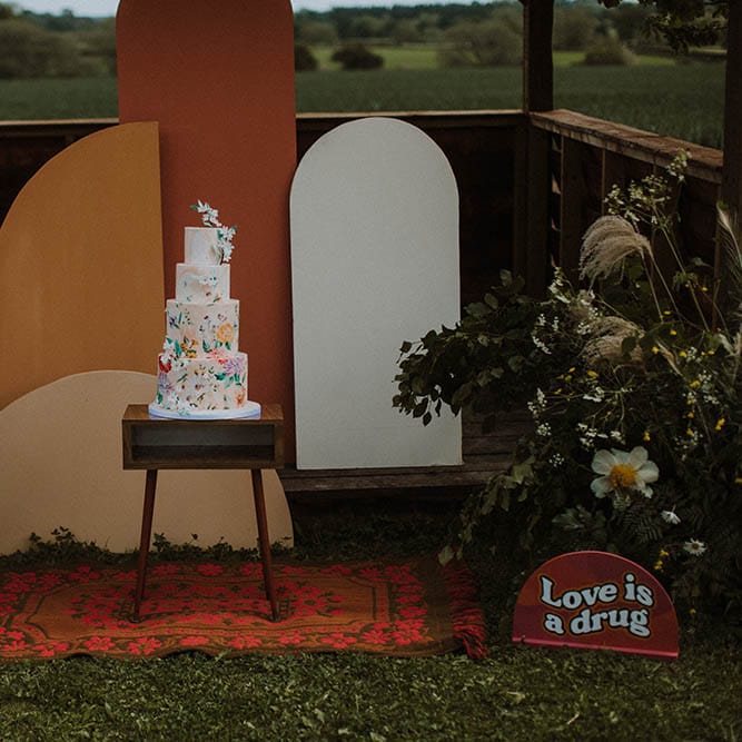 Geometric frame altar with wool rug, wild flowers and illustration wedding cake 