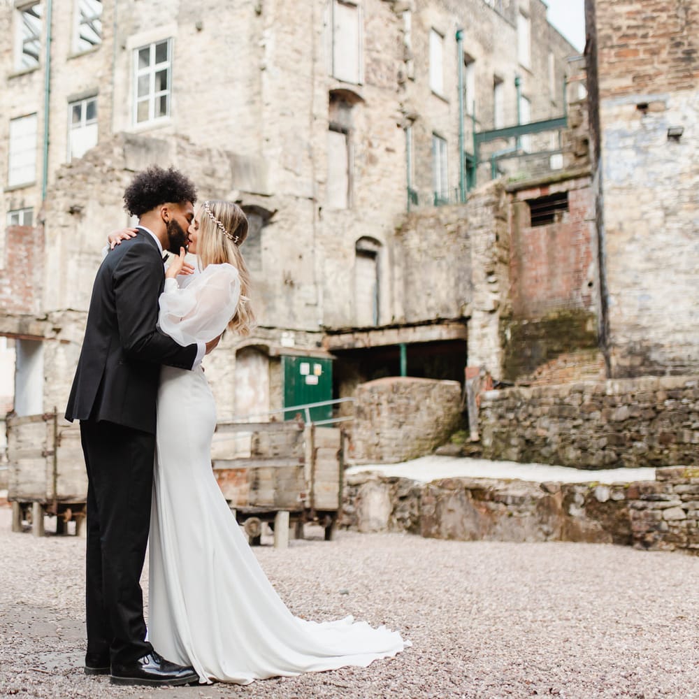 Stylish bride and groom kissing in the courtyard at Torr Vale Mill industrial wedding venue 