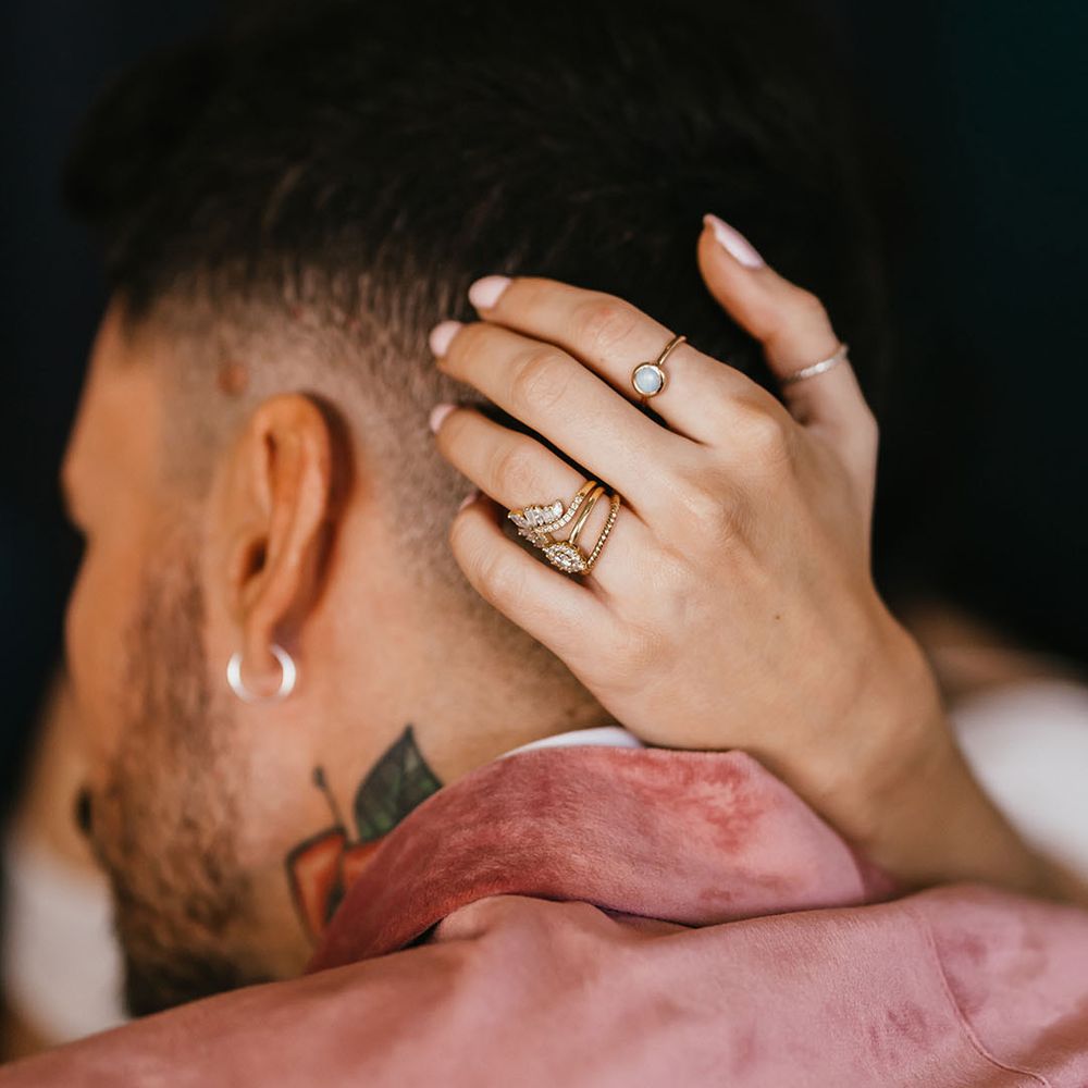 Bride with a wedding band and engagement ring stack embracing her grooms head 