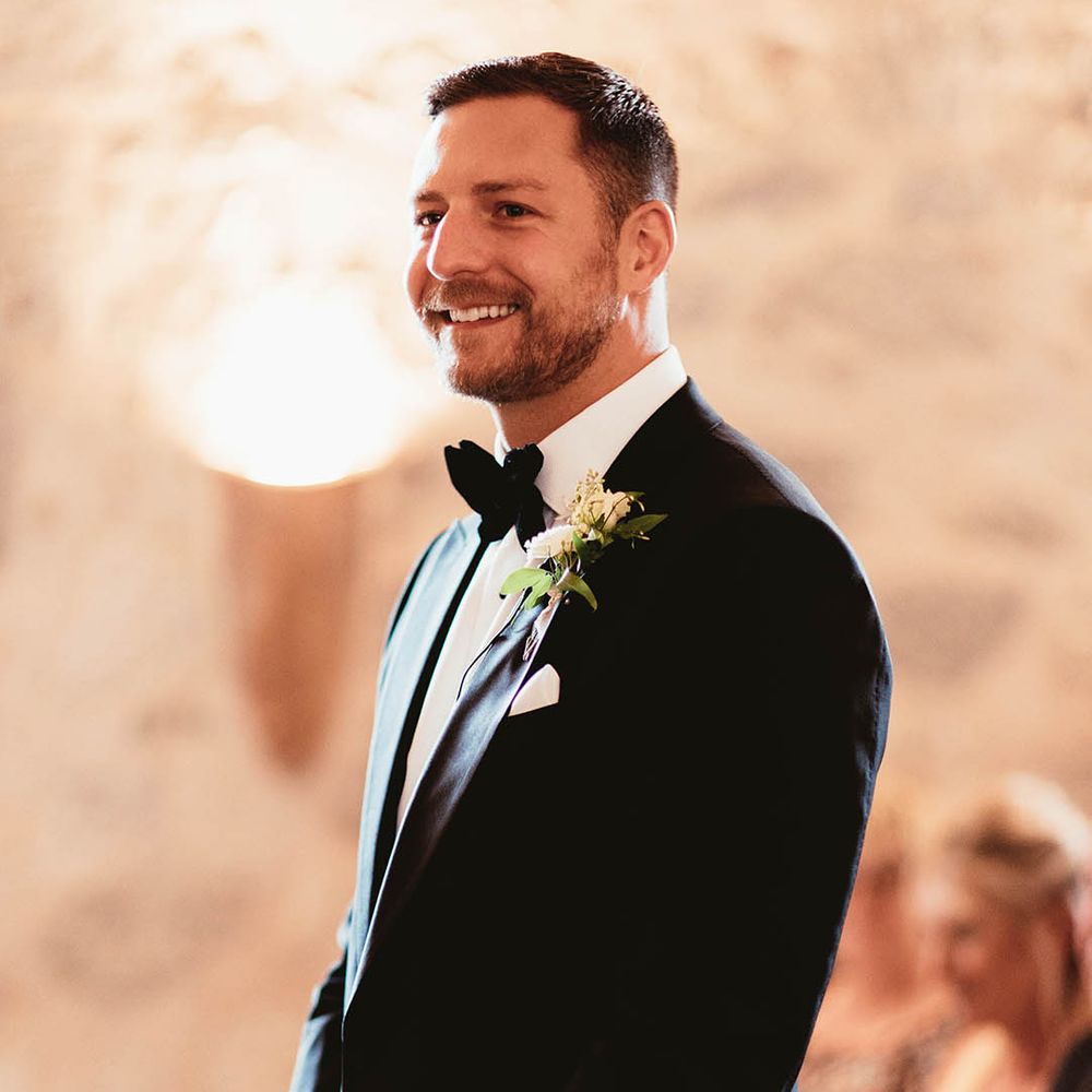 Grooms wears black tie as he awaits his bride on the day of his wedding during ceremony