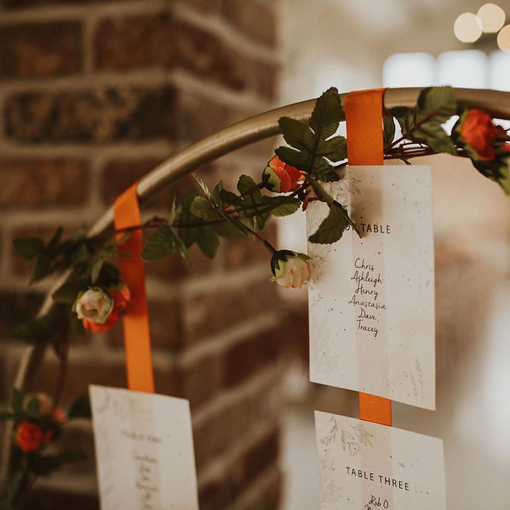 Gold hoop wedding table seating plan with orange ribbon