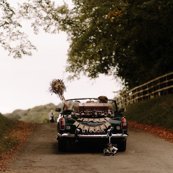 Bride and groom drive off in vintage wedding car 