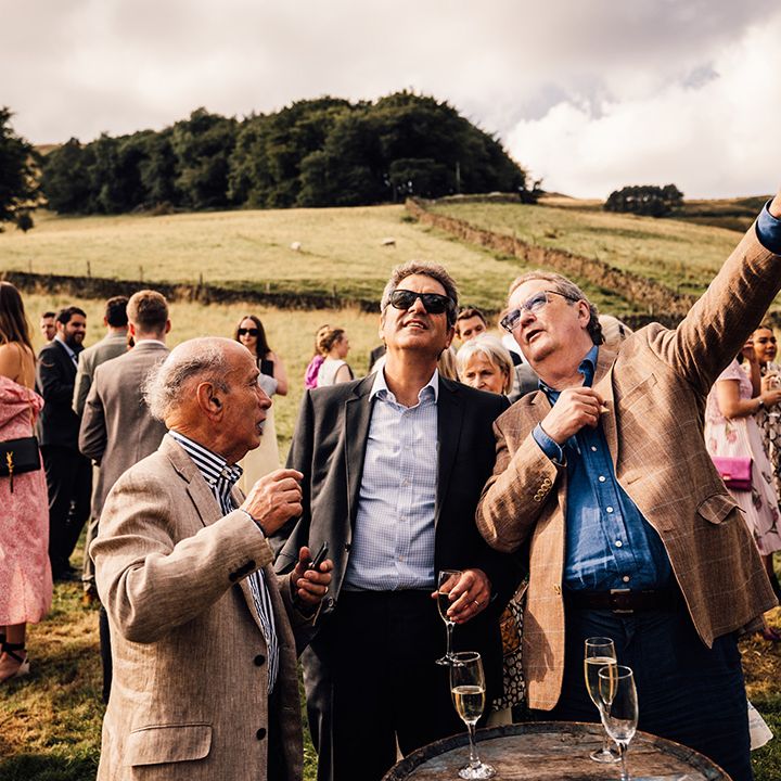 Wedding guests stand outdoors before ceremony