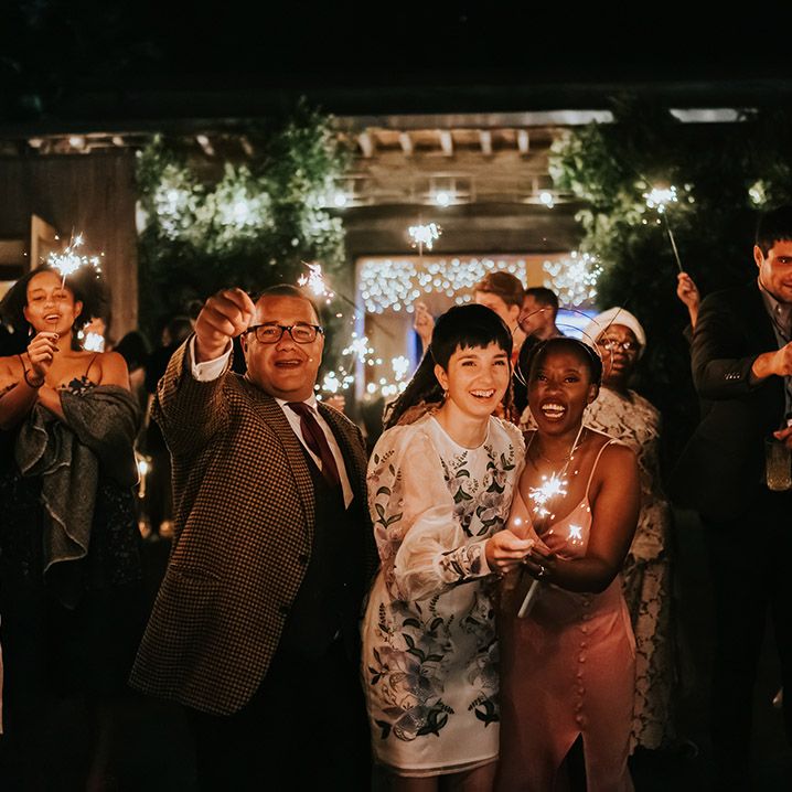 Sparkler moment with two brides in a pink satin midi dress and short embroidered dress 
