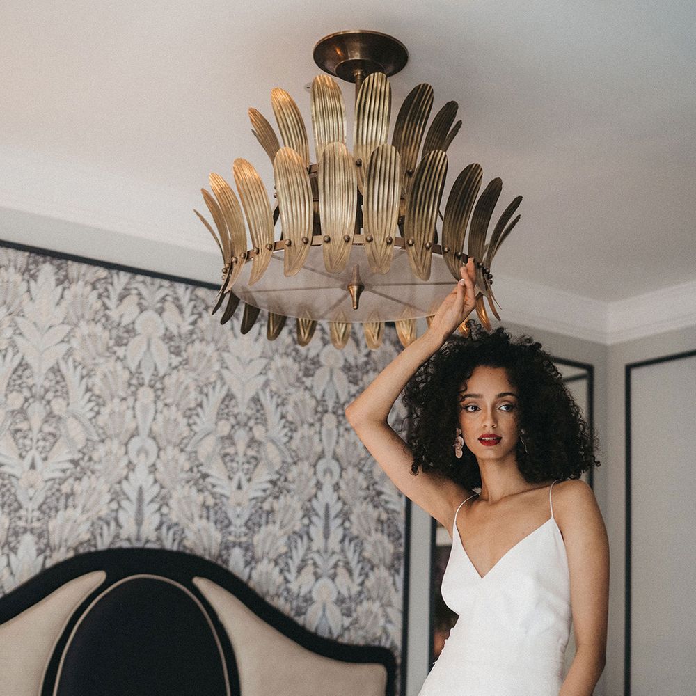 Black bride with naturally curly hair with winged eyeliner and red lipstick wearing an embroidered lace wedding skirt and camisole top