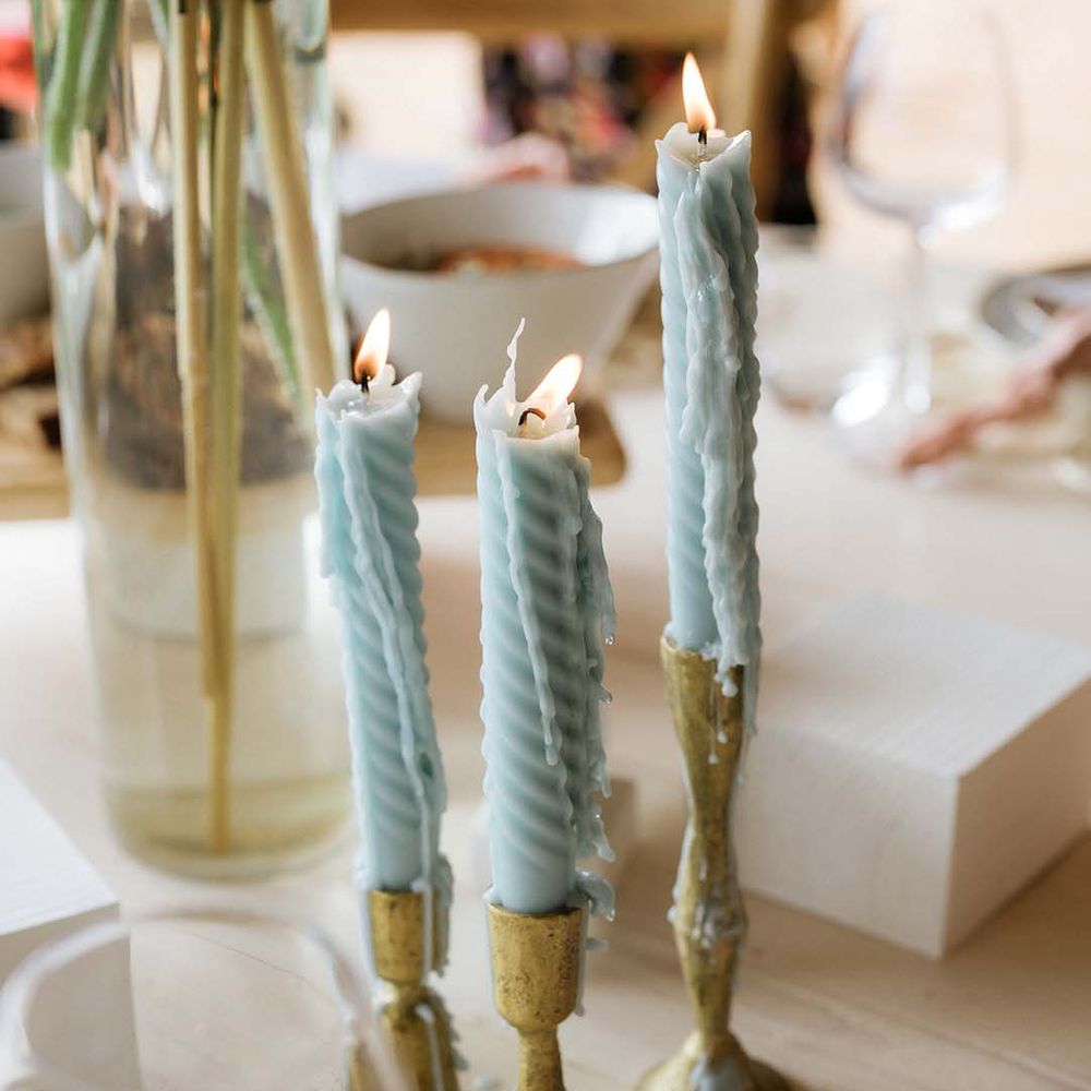 Twisted baby blue candles in golden candlestick holders as part of pastel theme for table settings