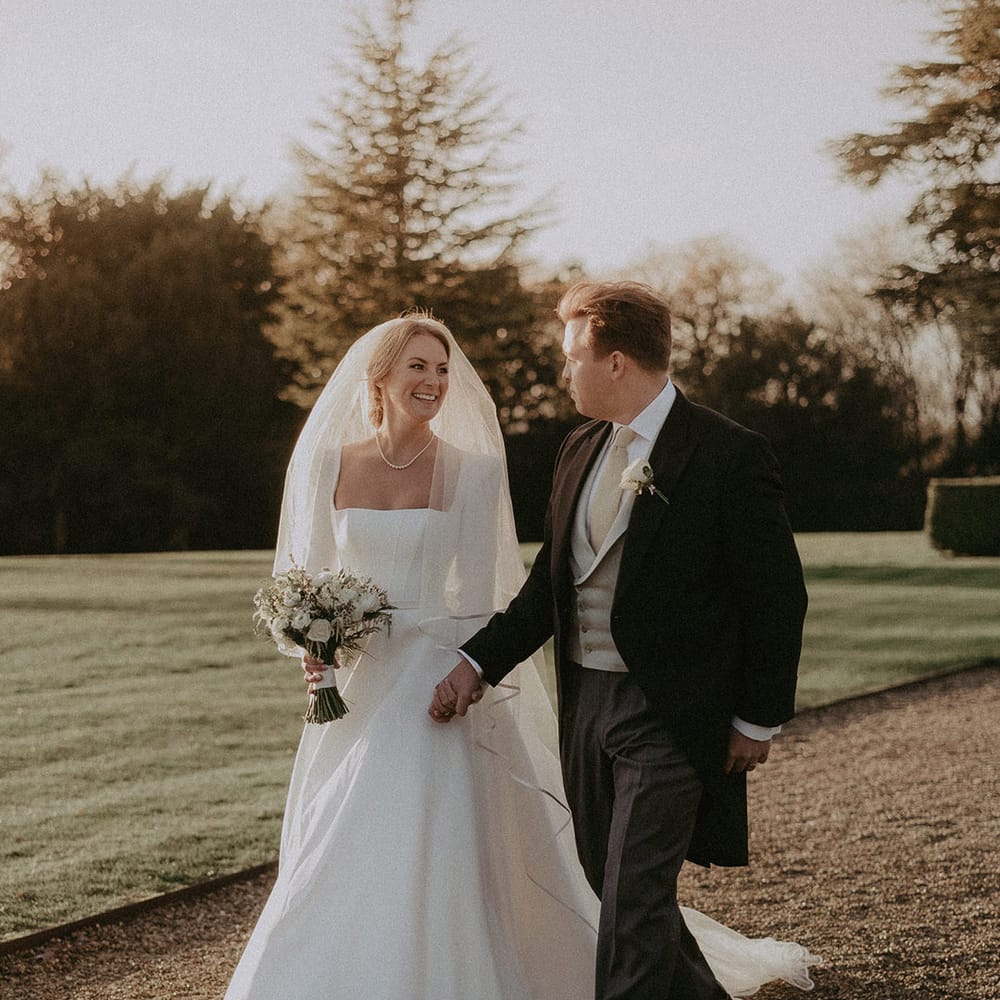 Bride in long white square neck long sleeved dress with full length veil and groom at Hedsor House wedding