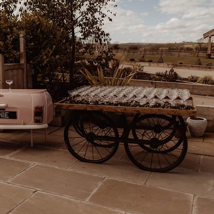 Mini bar made to look like a pink car with cart of cocktail glasses for wedding guests
