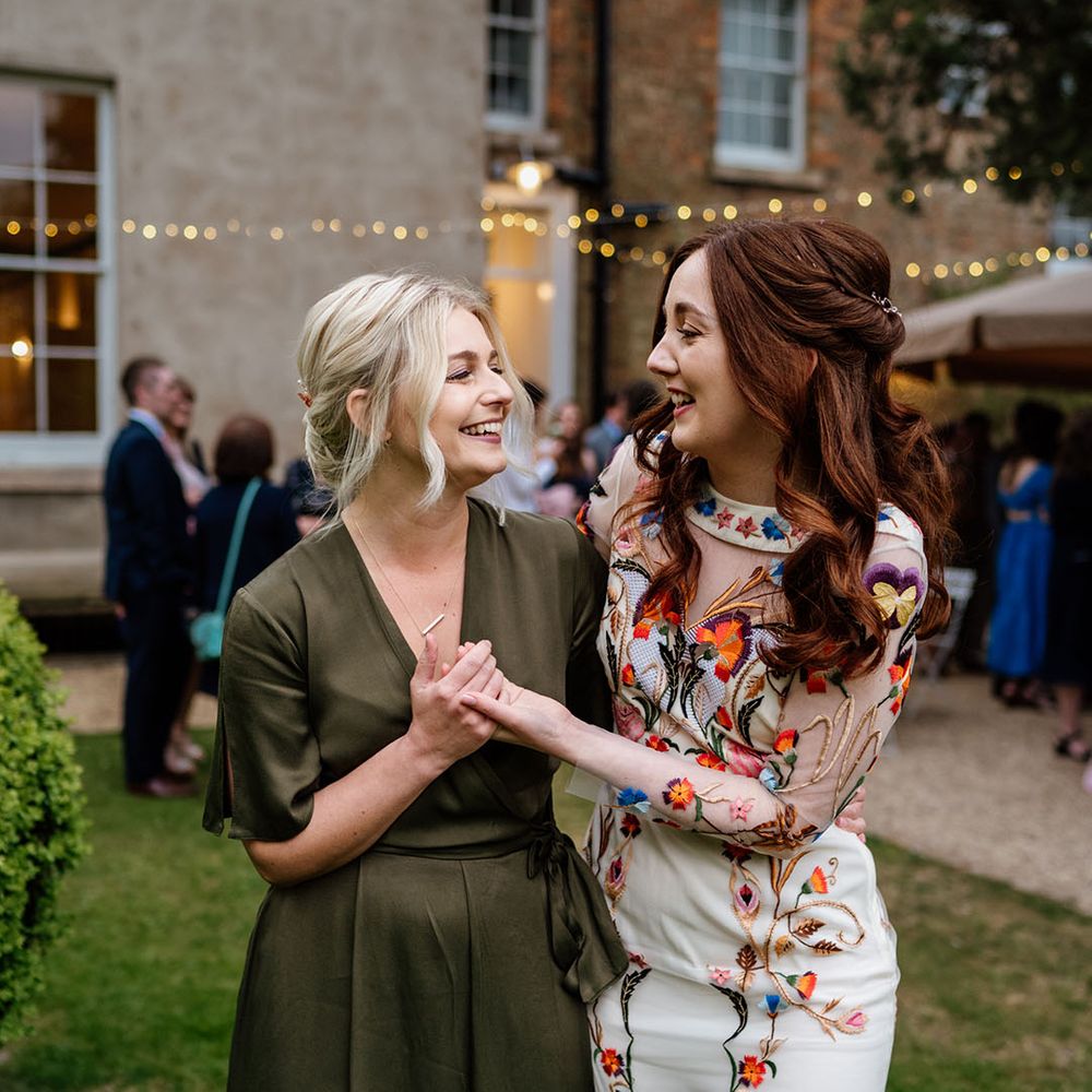 Bride in bright and colourful flower wedding dress with one of the bridesmaids in green wrap dress