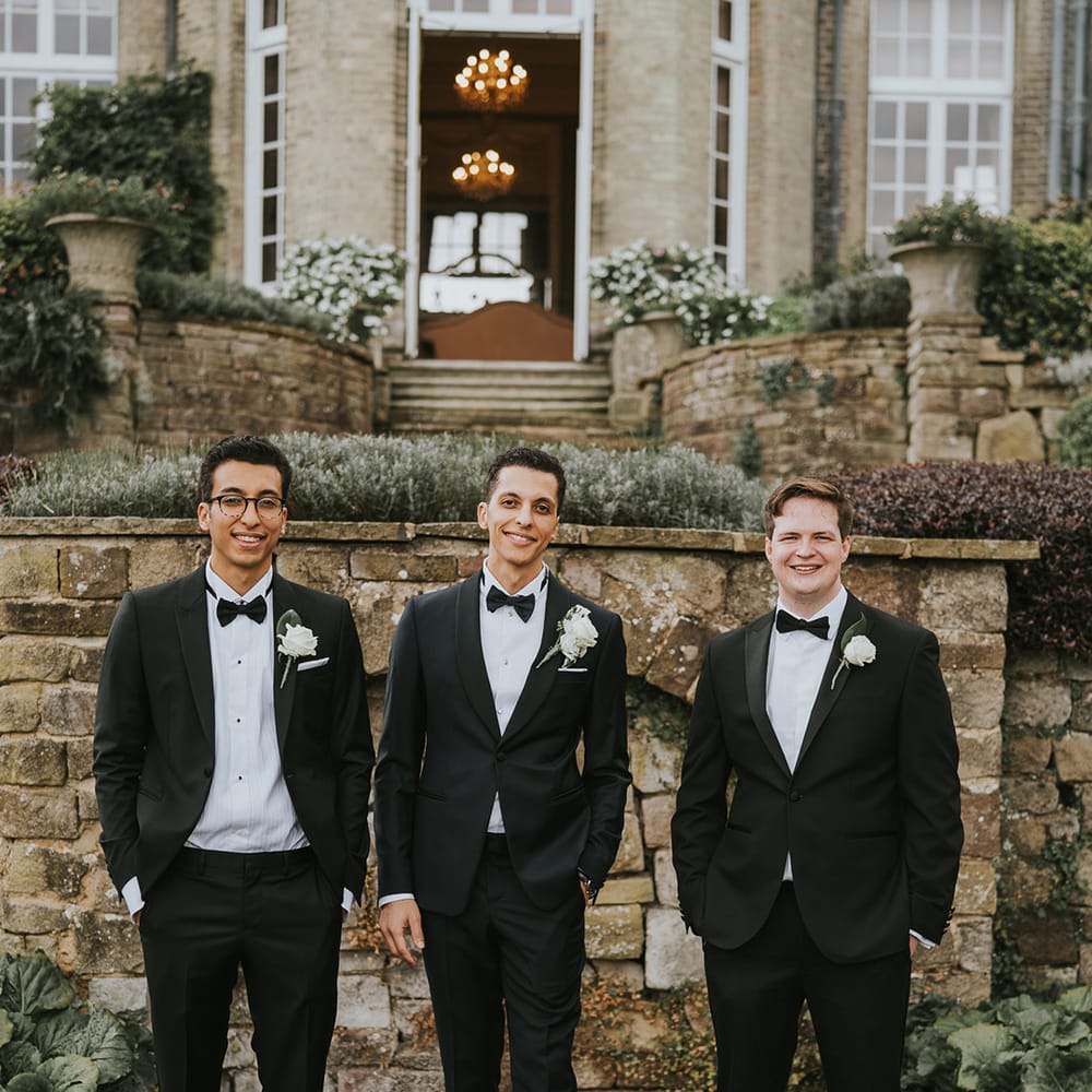 Groom with groomsmen in matching black tie outfits for wedding 