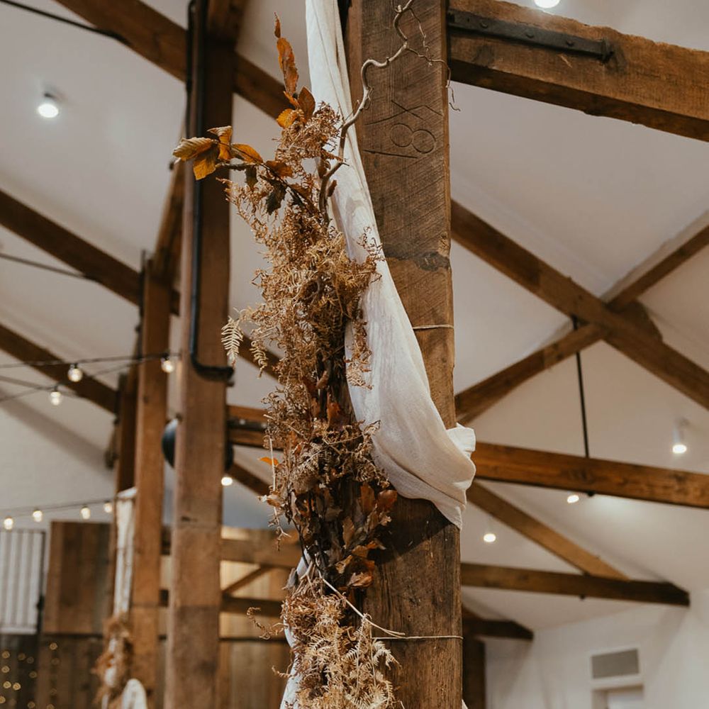 Dried autumnal grasses and leaves hanging with white wedding drapery 