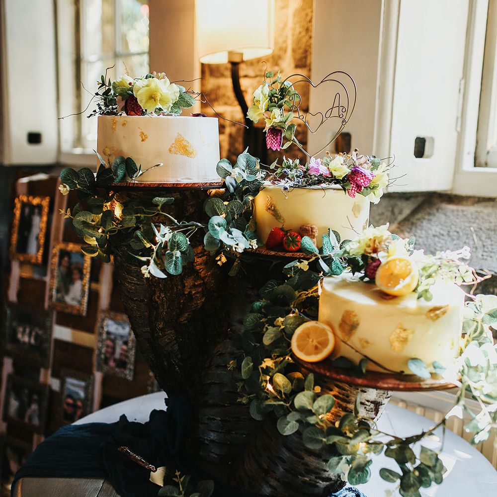DIY tree trunk cake stand finished with three white frosted wedding cakes and floral decor 