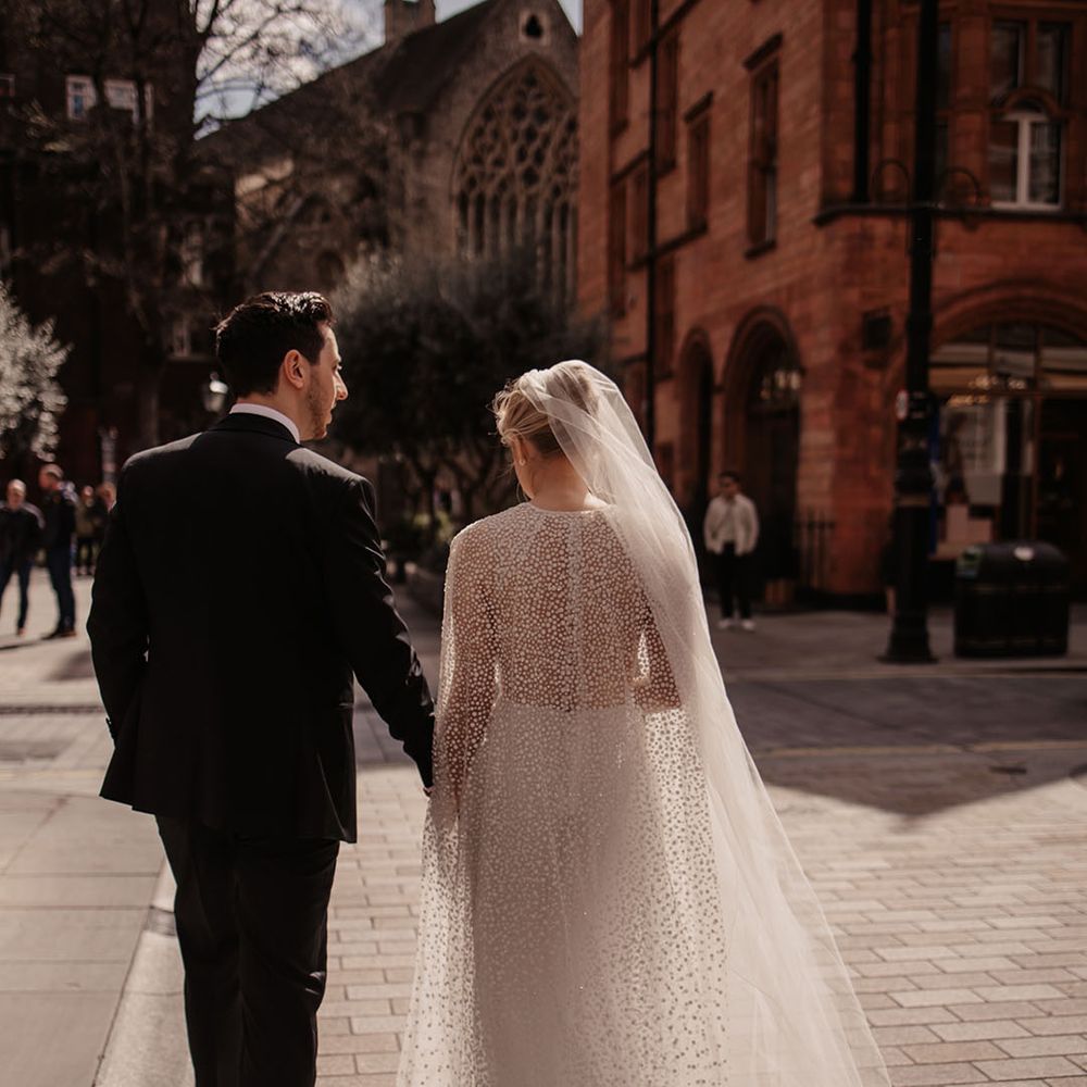 Bride in sparkly dotted wedding dress with groom walking in London 