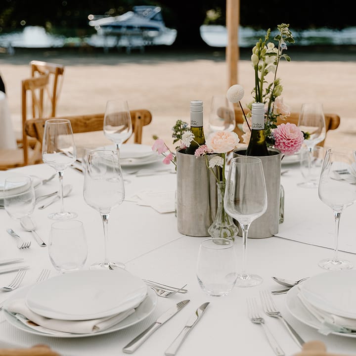 Classic tablescape complete with pastel florals in metal vases on rounded tables for outdoor reception