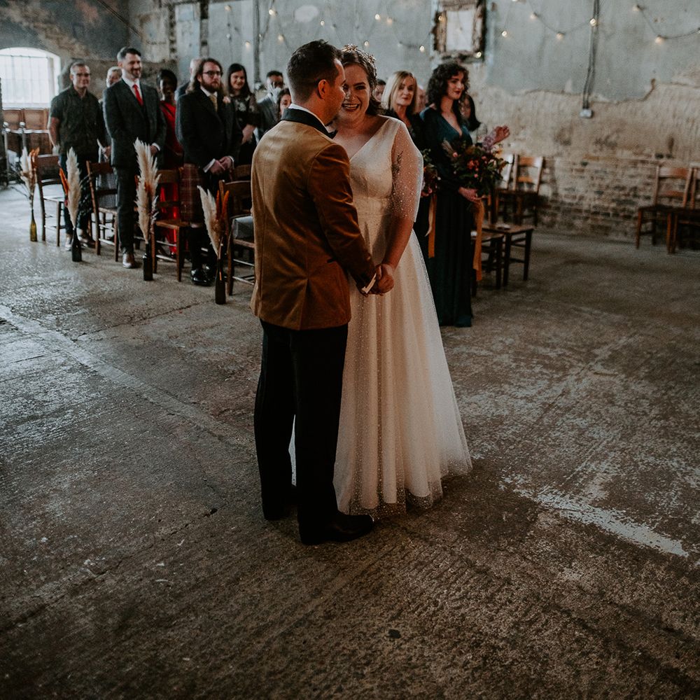 Couple holding hands and laughing at the alter in London wedding venue, The Asylum Chapel