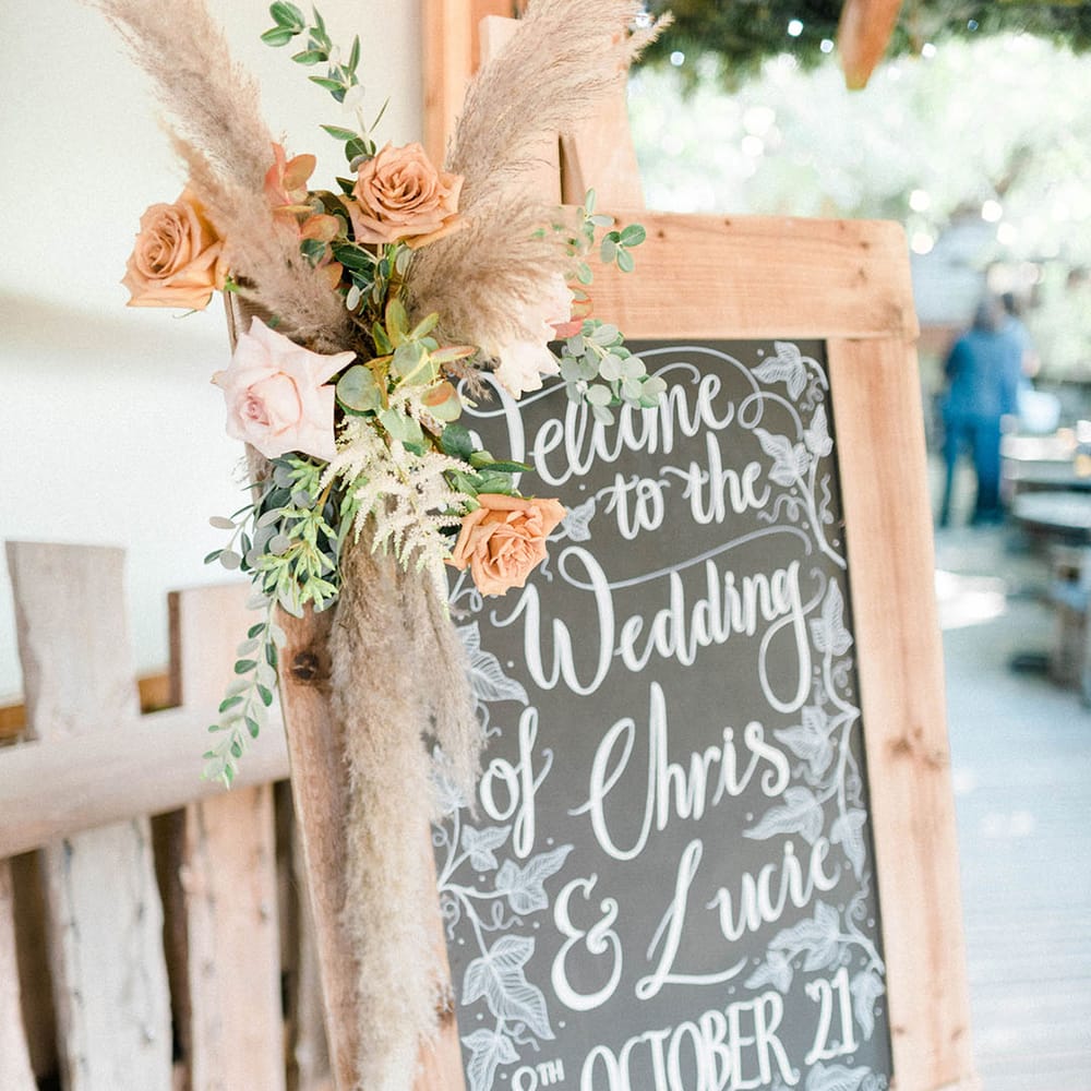 Chalkboard with wooden frame and dried floral decor to the side 