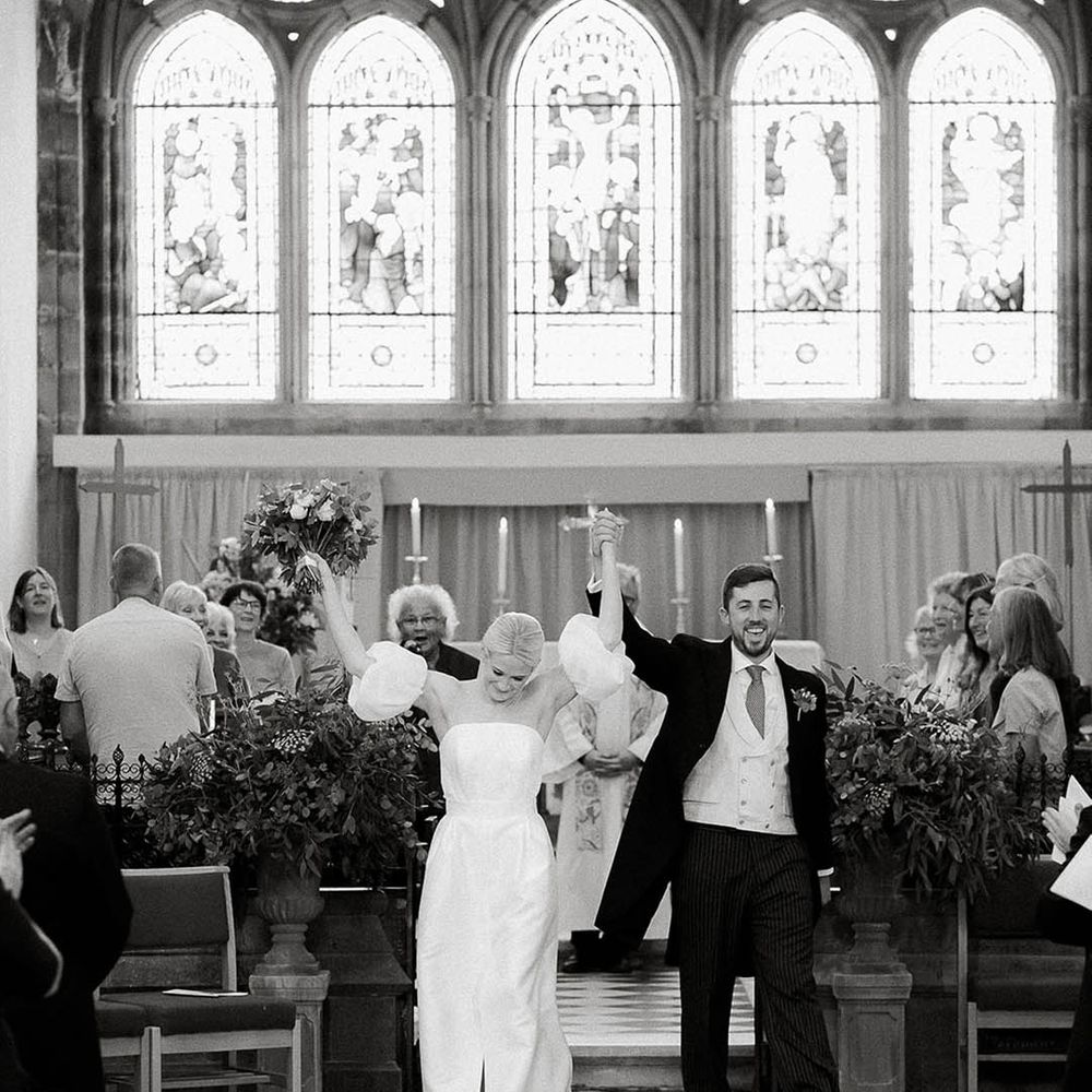 Bride in Jesus Peiro wedding dress celebrates with her groom after church wedding ceremony in Salcombe
