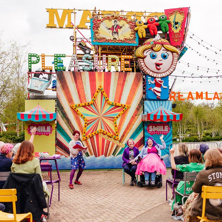 Margate Dreamland theme park wedding - brides sitting at the end of the alter in front of large colourful theme park ride 