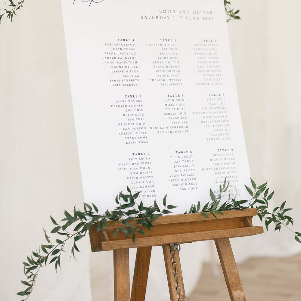 classic wedding table plan sign with green foliage on a wooden easel 