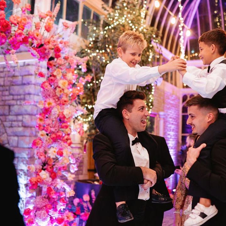 Groomsmen lift two boys on their shoulders to play at the wedding reception 