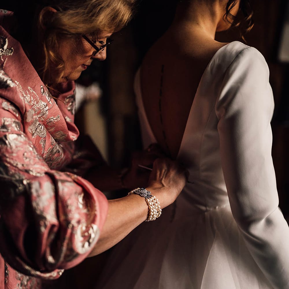 Mother of the bride in pink dress with gold embroidery with the bride in long sleeve wedding dress 