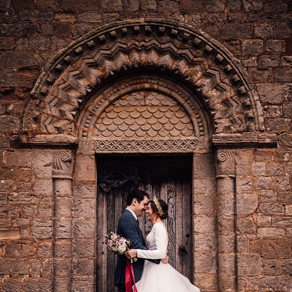 Bride in a ruffled bridal gown kissing the groom in a navy suit at Pauntley Court country house wedding venue 
