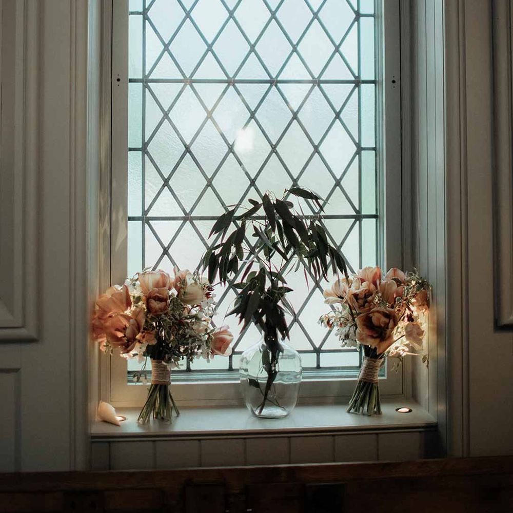 Wedding flower arrangements in glass jar vases on window ledge at The Dougarie Boathouse - wedding venues Scotland