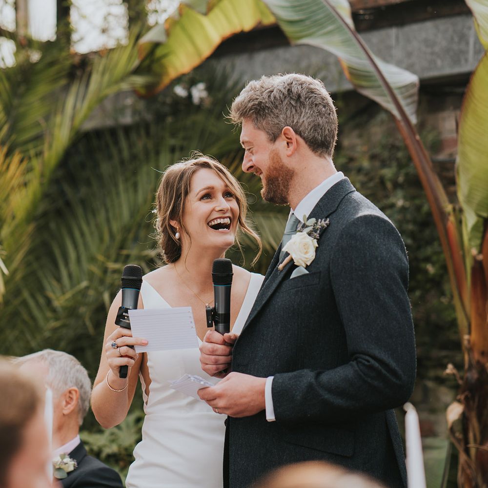 Bride and groom both holding microphones for their joint wedding speech at glasshouse wedding 