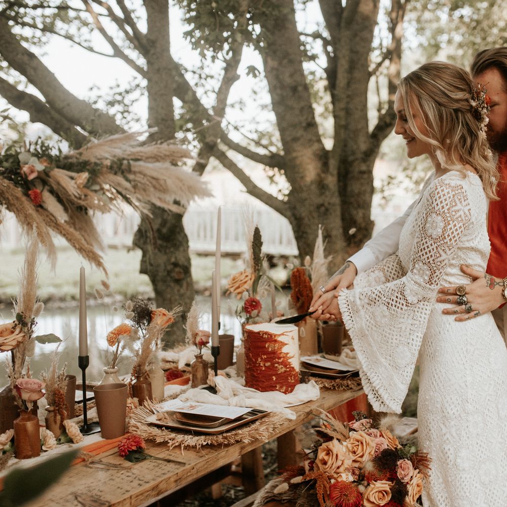 Bride & groom cutting wedding cake outdoors 