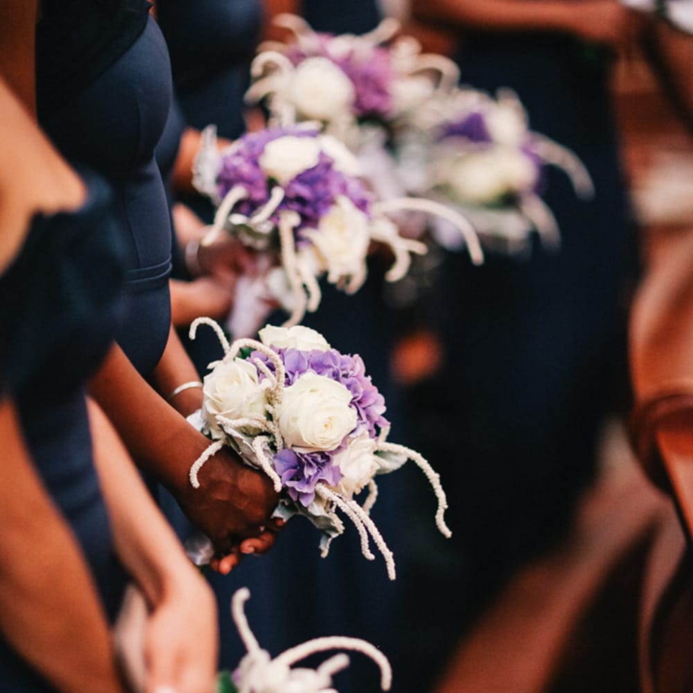 Bridesmaids holding purple wedding flower bouquets 