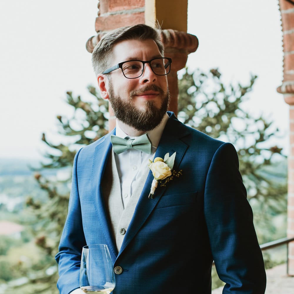 Stylish groom in a navy blue suit with pale green waistcoat and bow tie 