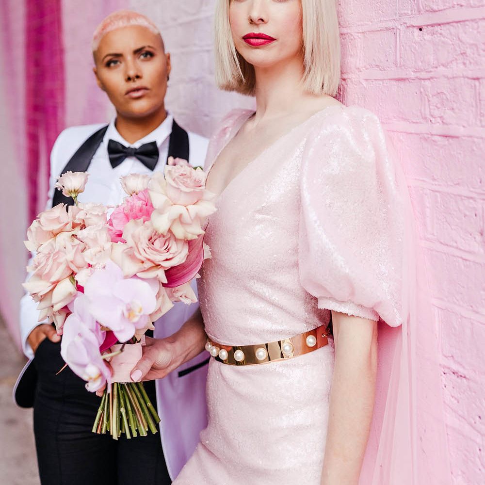 Blonde bride with bobbed hair wearing a shimmering pink jumpsuit with puff sleeves 