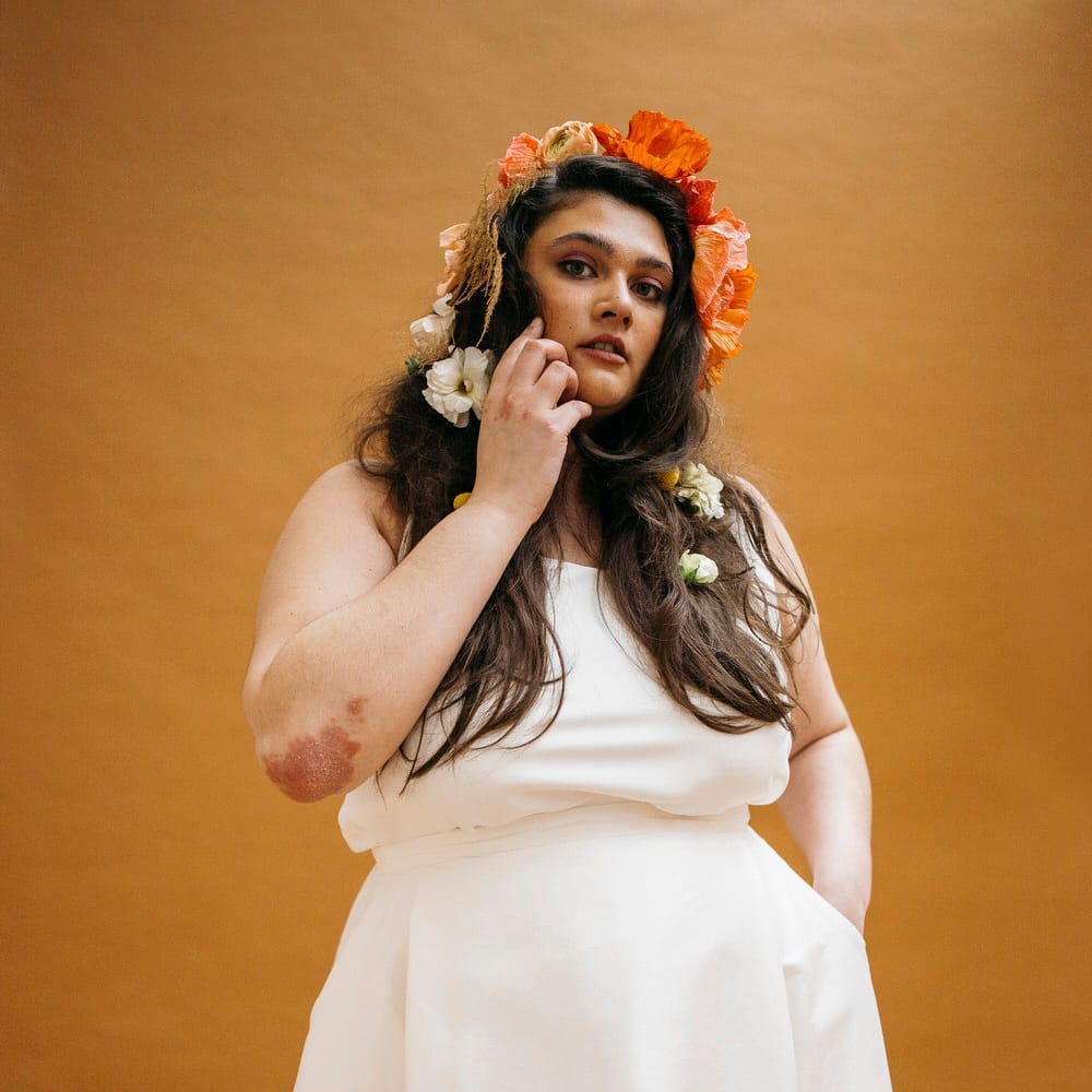 Bride wearing simple Paper To Lace wedding separates with hand painted illustrations, wearing orange flowers in her hair