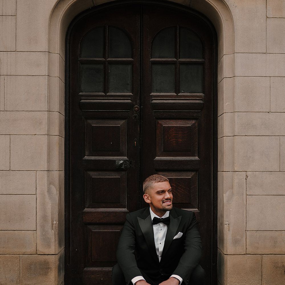 Stylish groom in a black tuxedo with shiny shoes and bow tie 