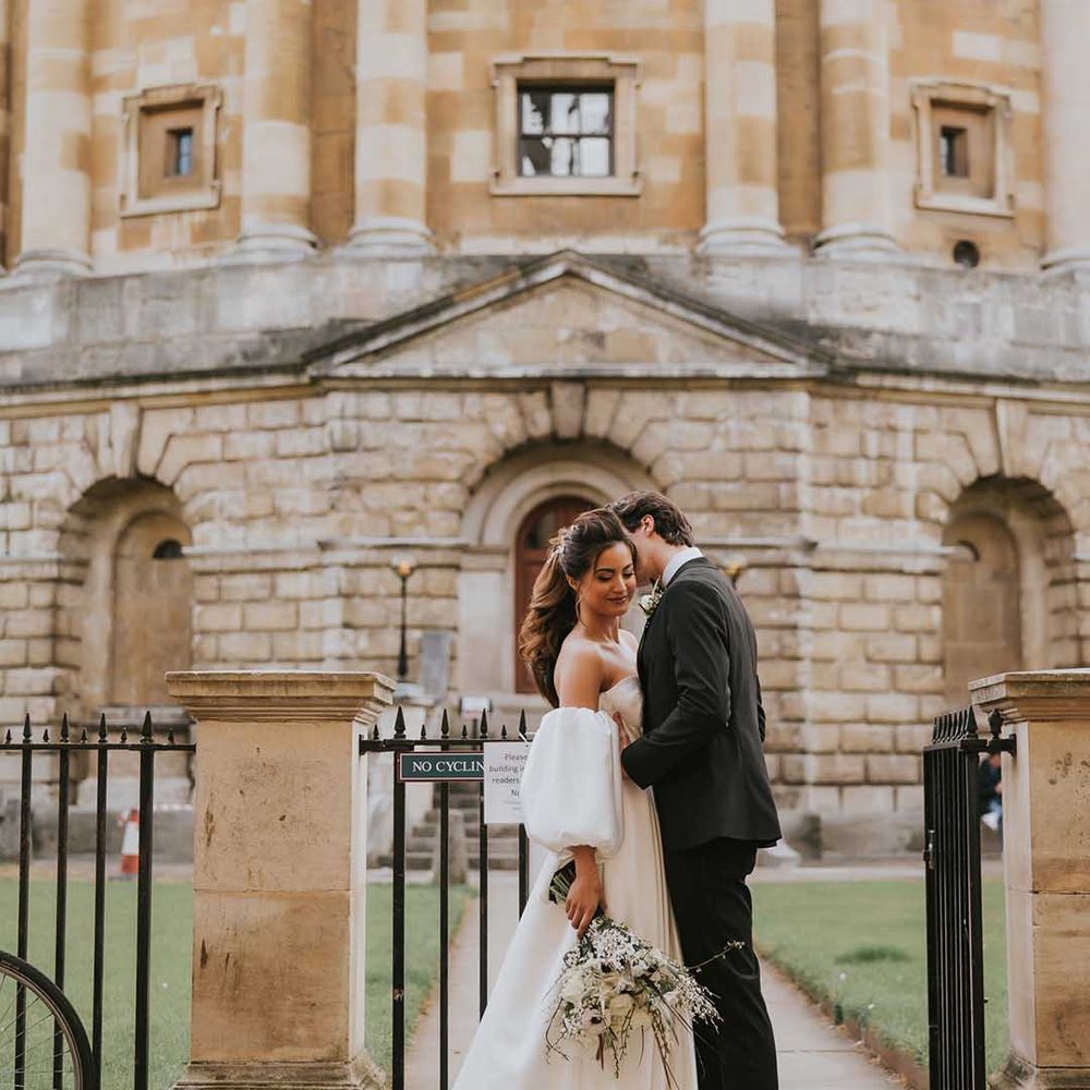Intimate bride and groom portrait outside Bodleian Library with bride in a strapless wedding dress with full skirt and detachable sleeves