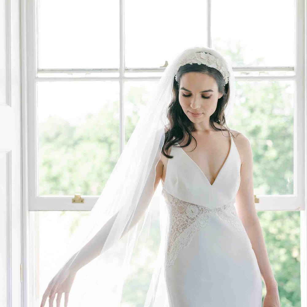 Bride in a slip wedding dress with lace inserts and a long cathedral length veil and appliqué headband 