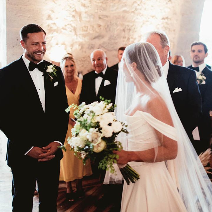 Bride wears Halfpenny London veil across her face whilst carrying classic white bouquet