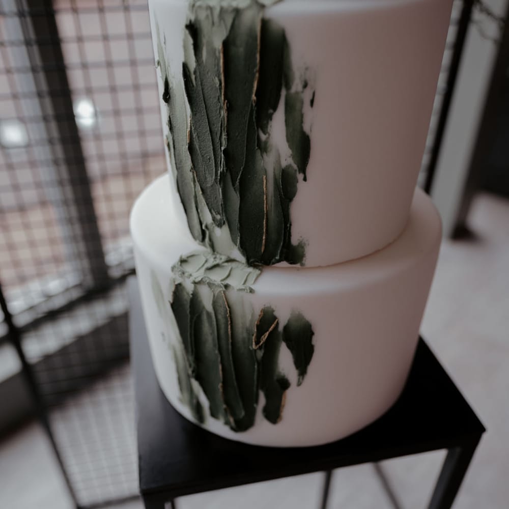 White iced wedding cake with forest green pattern cascading down the front 