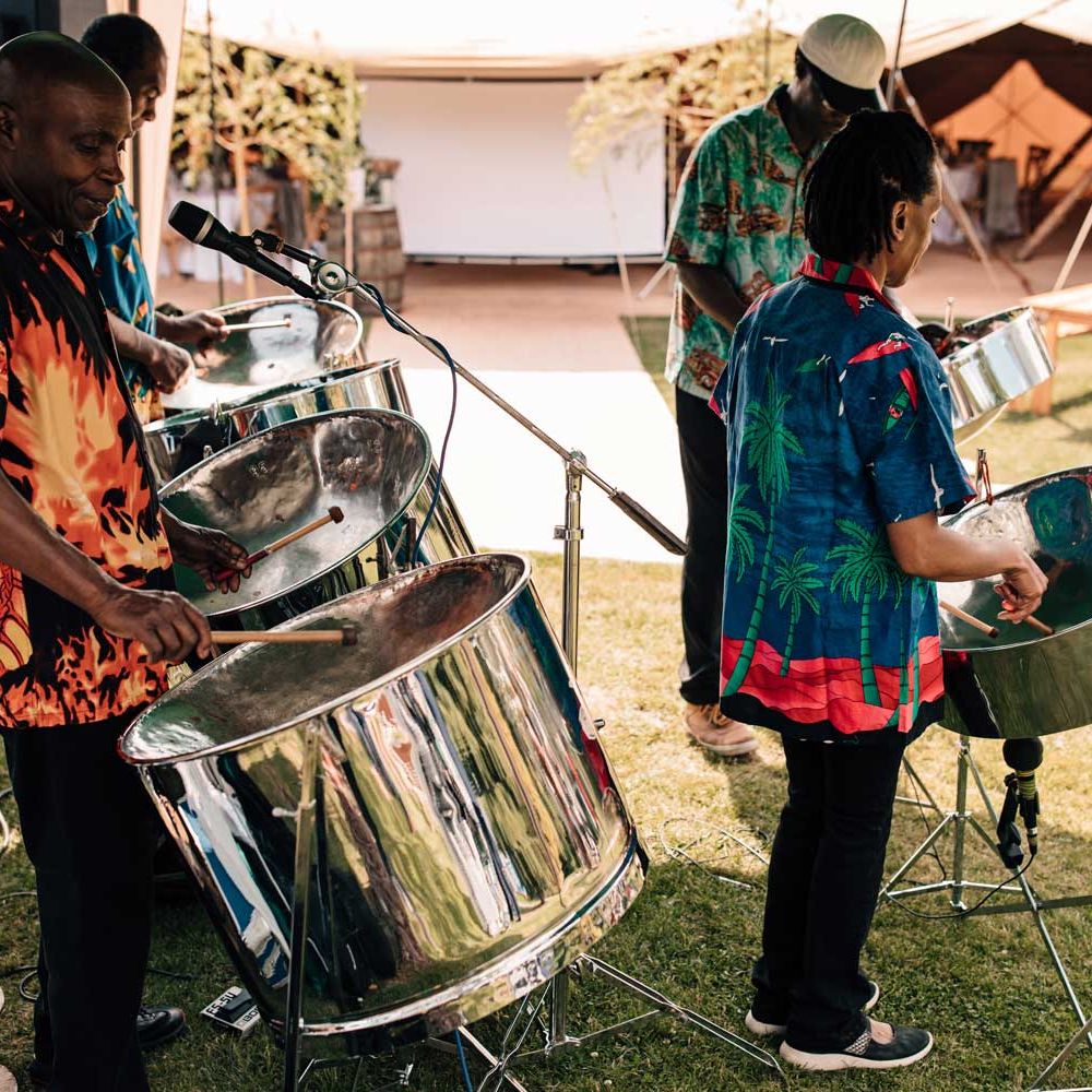 Band in brightly coloured short sleeved shirts plat steel drums for outdoor wedding reception 