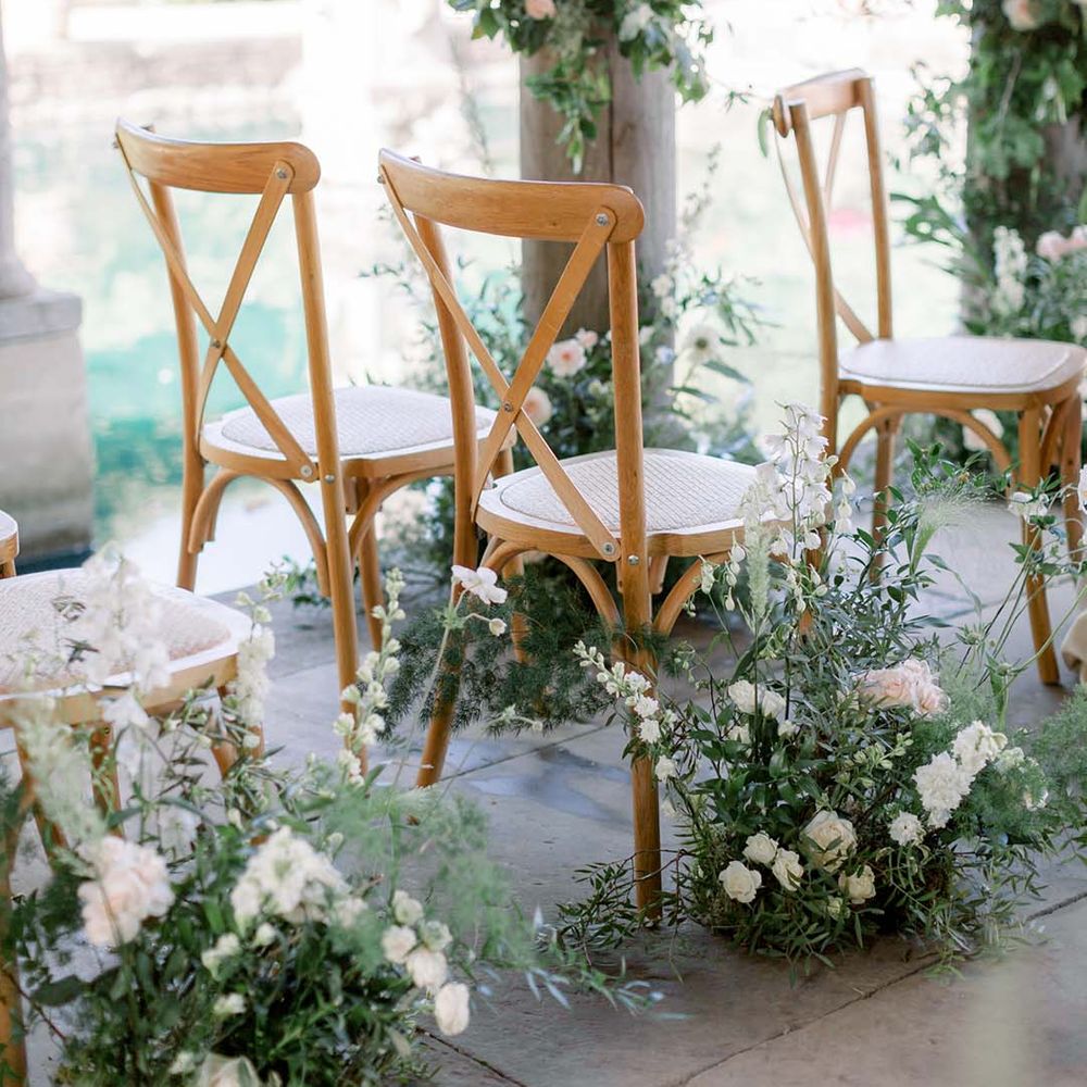 Wooden chairs surrounded by florals on wedding day