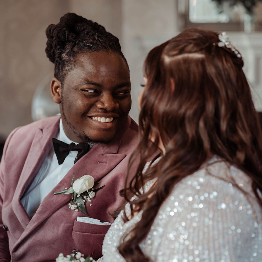 Groom looks lovingly at his bride who wears ASOS wedding gown